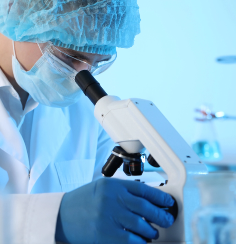 Cientifico con mascarilla mirando al microscopio